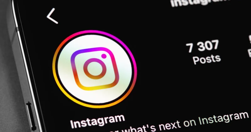 Зблизька показано екран смартфона з профілем Instagram, логотипом додатку, назвою "Instagram" та написом "7 307 Posts."