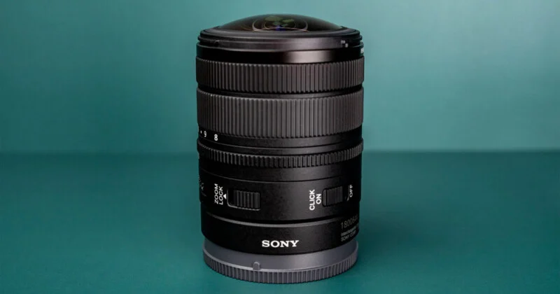 Чорний об'єктив Sony 8-14mm f/3.5 Fisheye G, що стоїть вертикально на бірюзовій поверхні.