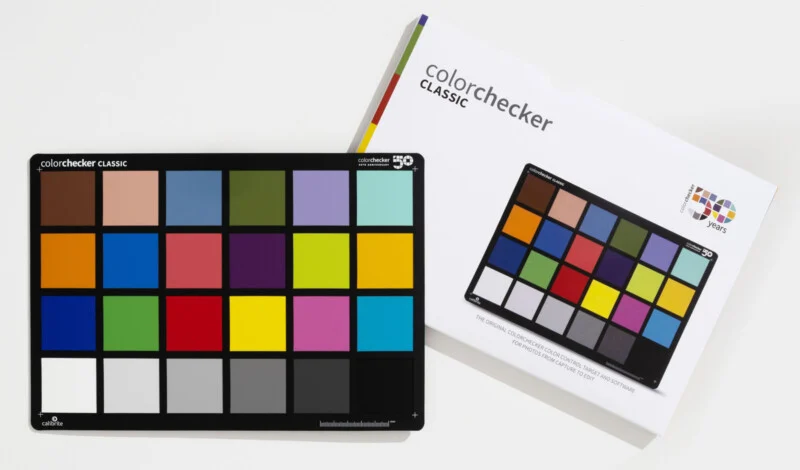Ціль Calibrite ColorChecker Classic поруч із білою пакувальною коробкою на чистому білому тлі.