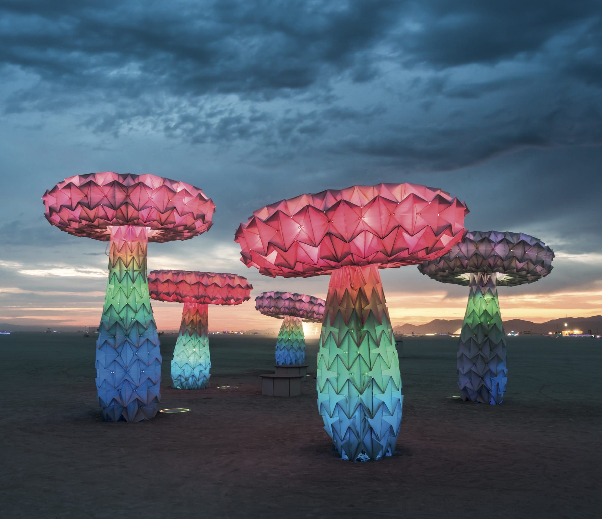 a collection of glowing outdoor mushroom sculptures at dusk