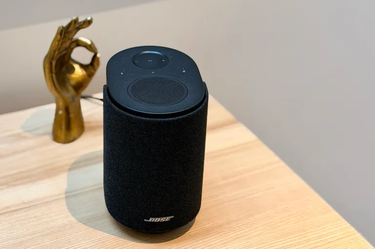 Акустична система Bose Lifestyle Ultra чорного кольору на тлі золотистої статуетки, що робить знак