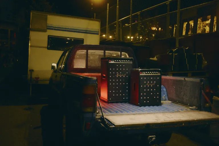 A Marshall Bromley 450 portable Bluetooth speaker sitting in front of a Bromley 750 transportable Bluetooth speaker in the flatbed of a pickup truck