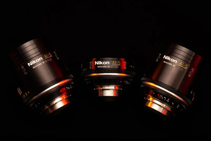 Три кінематографічні об'єктиви Nikon AI-S, перероблені TLS, розташовані на темному тлі з червоними та помаранчевими акцентами освітлення.