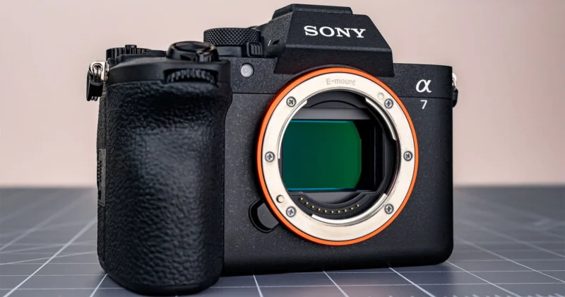 Чорний бездзеркальний фотоапарат Sony Alpha 7 з байонетом E лежить на сірій обробній дошці.