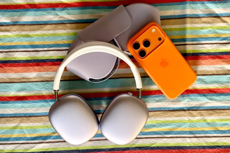 Фіолетові навушники AirPods Max 2 поруч з iPhone 17 Pro космічного кольору на різнокольоровій скатертині