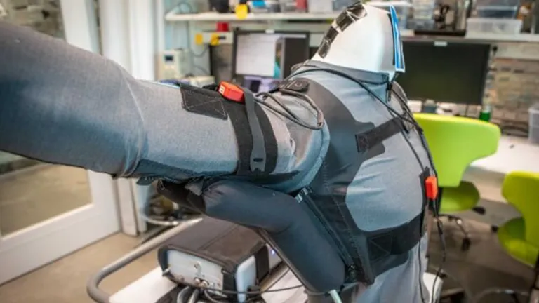 a wearable robot vest, with long grey sleeves and sensors in a lab