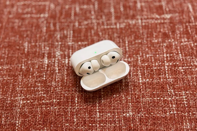 Білі навушники AirPods Pro 3 у відкритому футлярі на червоно-коричневій оббивці