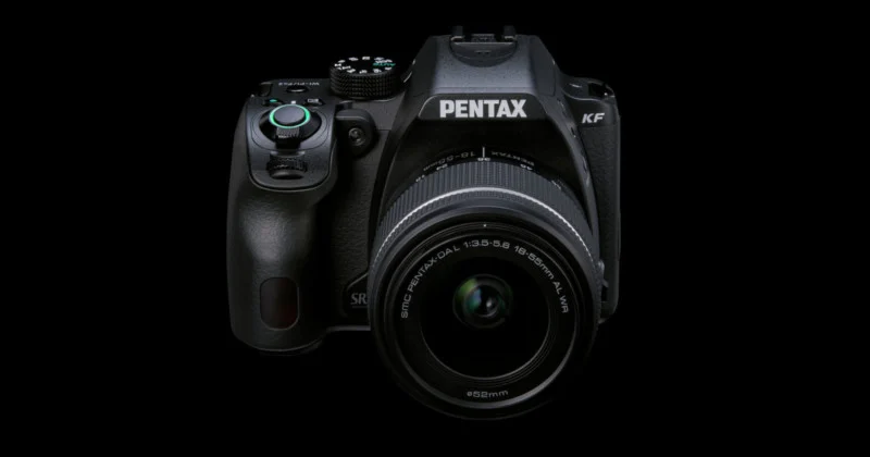 Чорна дзеркальна камера Pentax KF з об'єктивом 18-55 мм на темному фоні.