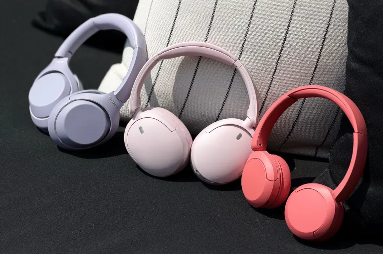 Нові навушники Sony WH-1000XM4C у лавандовому кольорі, WH-CH730N у рожевому та WH-CH530 у кораловому на чорно-білій подушці.