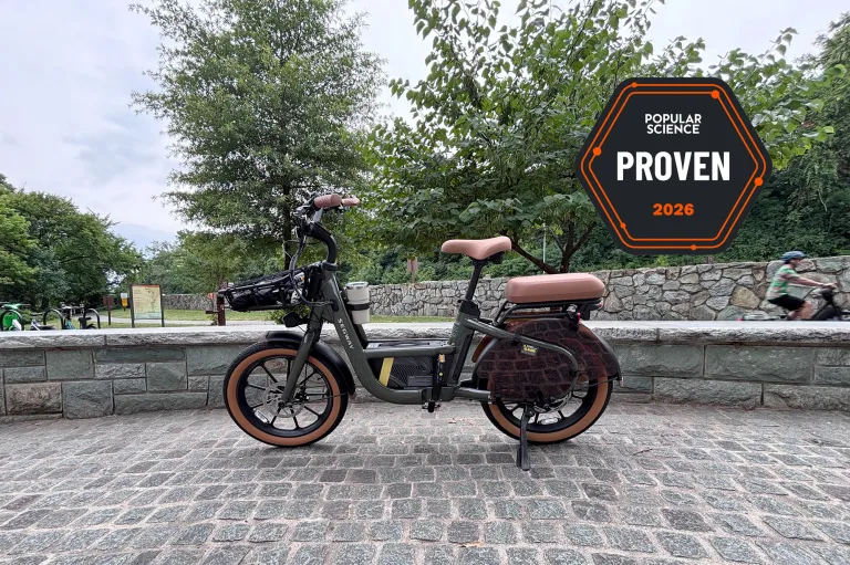 Вантажний електровелосипед Segway MUXI стоїть на бруківці поруч з велосипедною доріжкою Маунт-Вернон біля входу до острова Теодора Рузвельта. Значок PopSci Proven показано у верхньому правому куті.